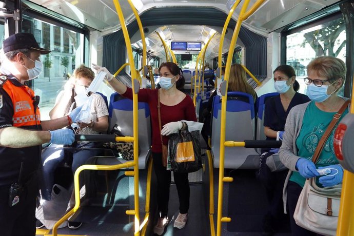 Miembros de protección civil de Málaga entregan mascarillas a los pasajeros de autobuses.