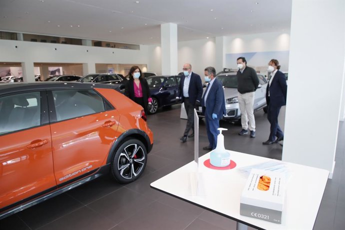 Imagen del interior de un concesioanrio con personas con mascarillas. 