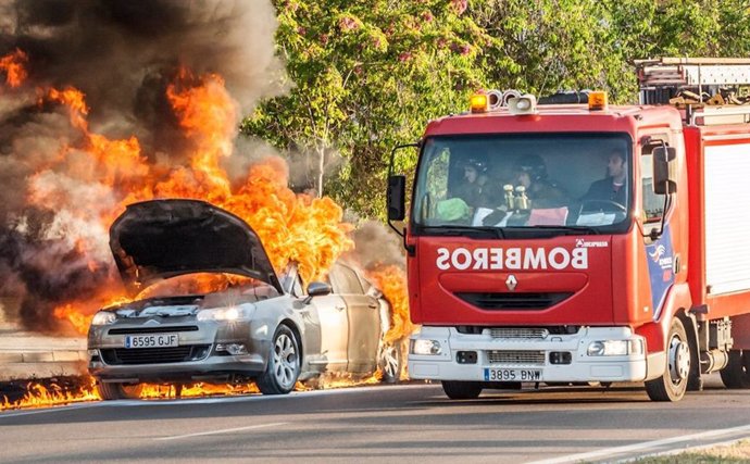 Un camió de bomberos de la Diputación de Badajoz junto a un coche ardiendo.