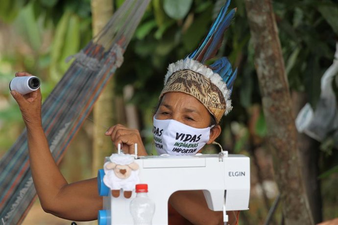 08 May 2020, Brazil, Tribes Park: An indigenous woman wearing a face mask sit at a sewing machine with which she makes face masks for the community to help protect against the spread of the coronavirus (COVID-19). Photo: Lucas Silva/dpa