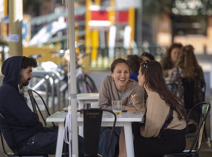 Un grupo de personas sentadas en los veladores de un bar, el día en el Sevilla pasa a la fase la fase 1 del plan de desescalada 