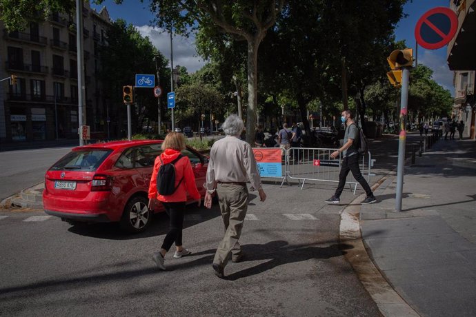 Transeúentes al lado de las vallas instaladas para cortar el tráfico lateral de la Diagonal, una de las medidas establecidas por el Ayuntamiento de Barcelona para ampliar los espacios para peatones. En Barcelona, Catalunya (España), a 13 de mayo de 2020.