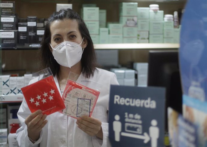 Una farmacéutica muestra una mascarilla en la Farmacia CEA, una de las 2.882 farmacias madrileñas que las distribuyen
