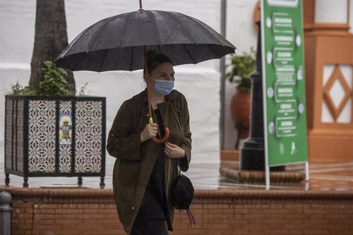 Una mujer protegida de la lluvia bajo un paraguas, en el municipio de Almonte, durante el tercer día de la Fase 1 del plan de descalada que ha elaborado el Gobierno de España. En Almonte, Huelva (Andalucía, España), a 13 de mayo de 2020.