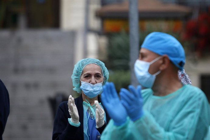 Bomberos realizan junto a trabajadores de Correos el aplauso a los sanitarios, en la puerta principal del Hospital Regional de Málaga.