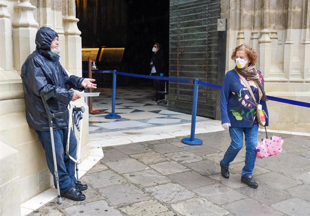 Ciudadanos salen de la  Catedral de Sevilla ante la presencia de un indigente  el primer día de la fase 1 por la pandemia del coronavirus. Sevilla a 11 de mayo del 2020