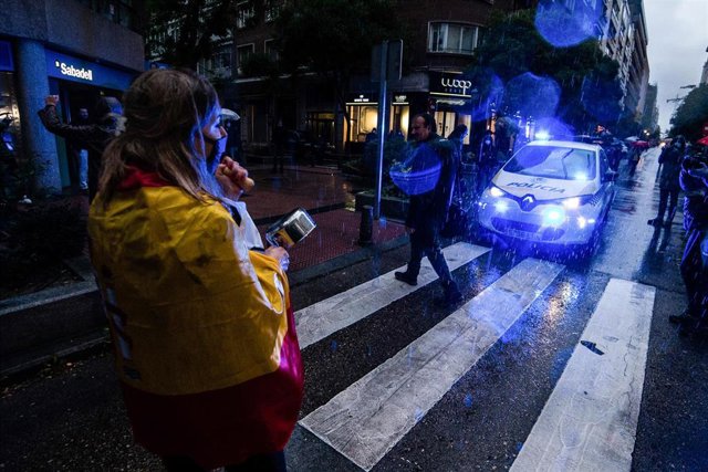 Una mujer se coloca delante de una patrulla de Policía Municipal en señal de protesta durante la concentración de los vecinos del barrio madrileño de Salamanca en la calle Núñez de Balboa 