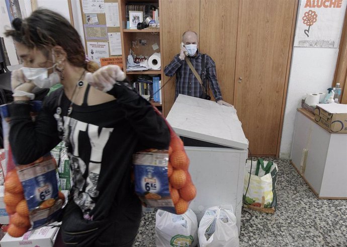 Voluntarios de la Asociación de Vecinos Parque Aluche colocan alimentos en la calle Quero n 69 para luego repartirlos el fin de semana. En Aluche, Madrid, (España), a 13 de mayo de 2020.