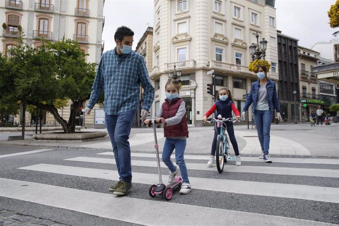 Una familia  cruzan un paso de peatones por la calle el primer día en el que los menores de 14 años pueden salir. En Granada (Andalucía ,España) a 26 de abril de 2020.