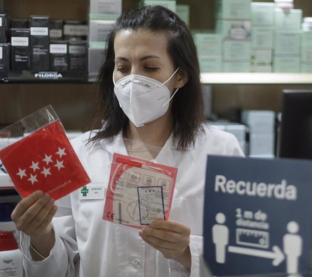 Una farmacéutica muestra una mascarilla en la Farmacia CEA, una de las 2.882 farmacias madrileñas