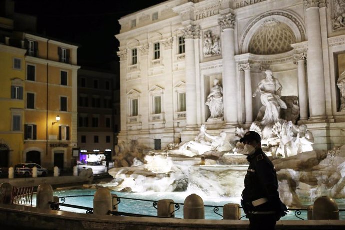 Un policía con mascarilla frente a la Fontana di Trevi en Roma