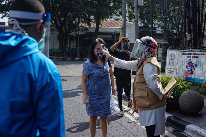 Un profesional sanitario toma la temperatura a una mujer en Indonesia, en el marco de la pandemia del coronavirus. 