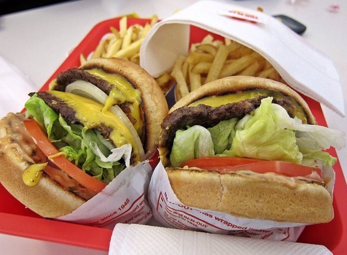 Imagen de dos hamburguesas para retratar con facilidad el exceso de grasas saturadas en la comida basura.