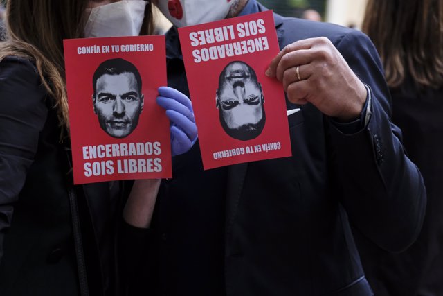 Un hombre y una mujer sujetan un panfleto contra Sánchez durante la concentración de protesta contra Sánchez en la calle Núñez de Balboa de Madrid.