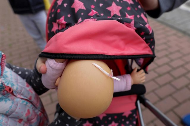 Una niña pasea por la calle empujando un carrito con un bebé de juguete. En Madrid (España) a 27 de abril de 2020.