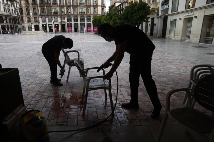 Trabajadores de la cafetería Central ubicada en la Plaza de La Constitución, en Málaga se afanan en la limpieza de los enseres de la terraza en caso de poder abrir el lunes 18 de mayo (Málaga a 20 de mayo del 2020)