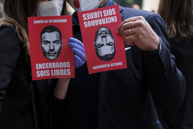 Un hombre y una mujer sujetan un panfleto contra Sánchez durante la concentración de protesta contra Sánchez en la calle Núñez de Balboa. En Madrid, a 14 de mayo de 2020.
