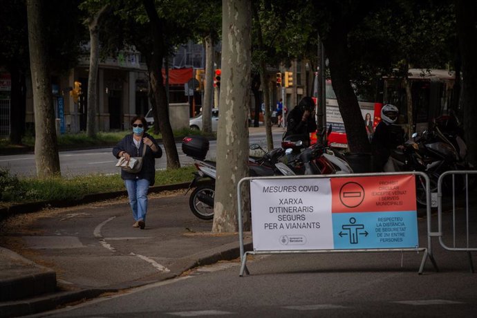 Una mujer pasa al lado de las vallas instaladas para cortar el tráfico lateral de la Diagonal (Diagonal-Sant Joan). En Barcelona, Catalunya (España), a 13 de mayo de 2020.