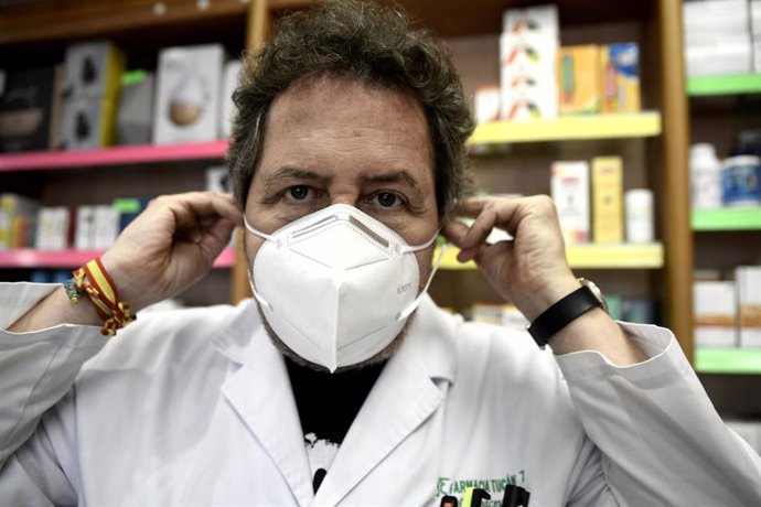 Un farmacéutico se coloca una de las siete millones de mascarillas FFP2 modelo KN95 que a partir de hoy las farmacias reparten gratuitamente entre la población de la Comunidad de Madrid. En Madrid (España), a 11 de mayo de 2020.
