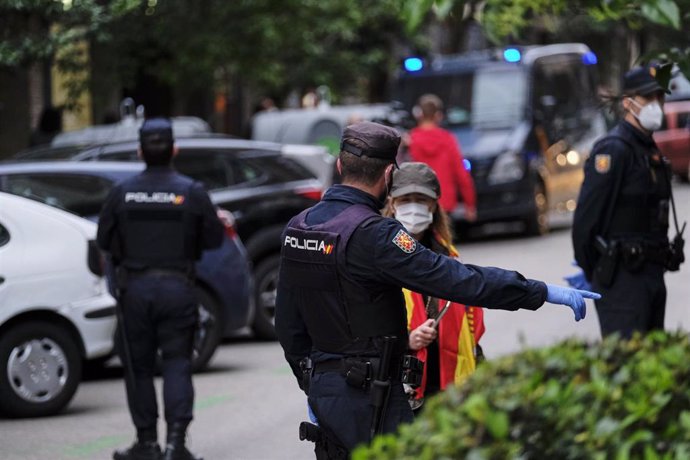 Un policía nacional da una indicación a una mujer en la concentración de protesta contra Sánchez en la calle Núñez de Balboa de Madrid.