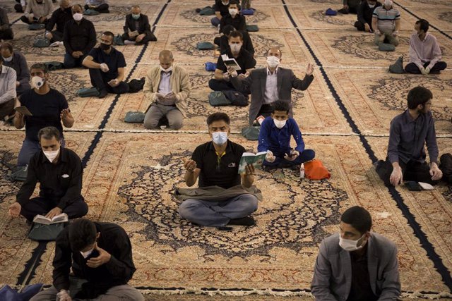 Hombres rezando con mascarilla en una mezquita en Teherán