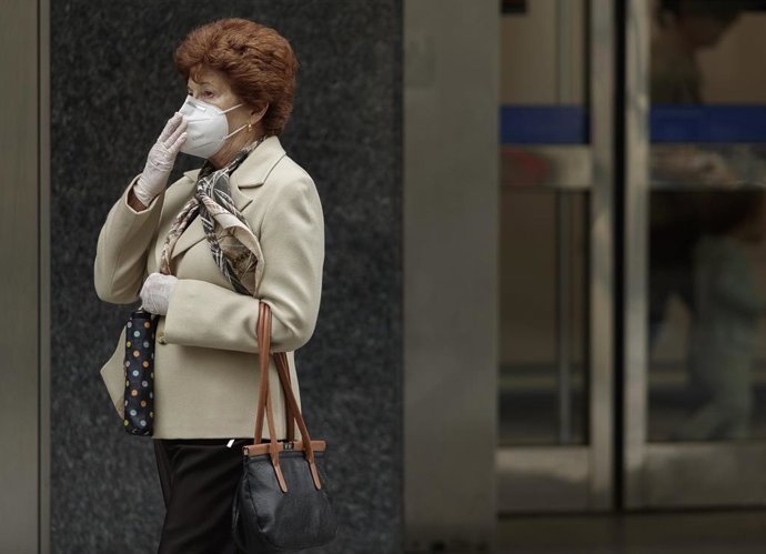 Una mujer camina con una mascarilla por la capital