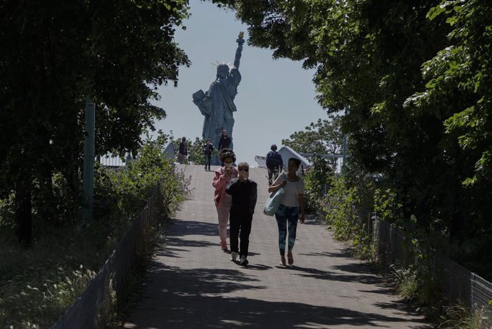 Franceses con mascarilla junto a la Estatua de la Libertad de París