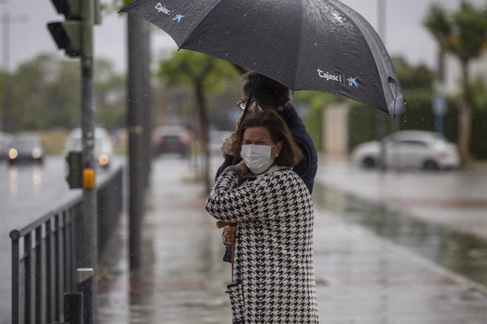 Dos personas bajo un paraguas durante una tormente durannte el estado de alarma en una imagen de archivo.