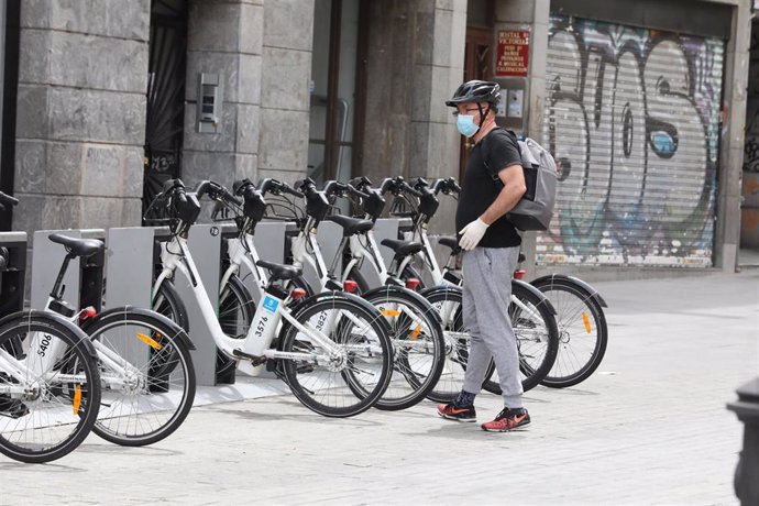 Un hombre coge una bicicleta de bicimad aparcada en una calle de la capital 