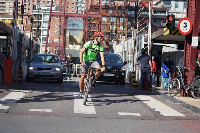 Un ciclista y dos coches cruzan el Puente de Vizcaya, que une los dos márgenes de la ría de Bilbao en Vizcaya y enlaza la villa de Portugalete con el barrio de Las Arenas, que pertenece al municipio de Getxo