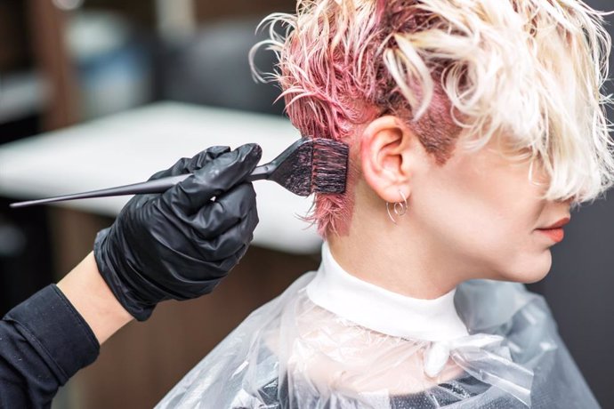 Mujer tiñéndose el pelo en una peluquería, tinte.