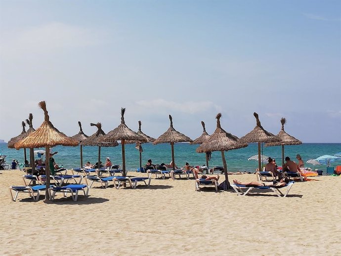 Turistas en hamacas bajo las sombrillas de la Playa de Palma, el verano pasado.