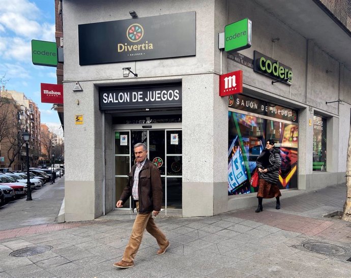 Dos personas pasan junto a un salón de juegos de Madrid.