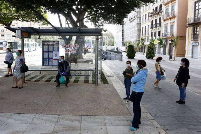 Varias personas esperando el autobús guardan la distancia de seguridad, en Málaga