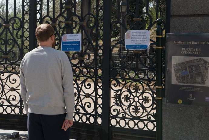 Un transeúnte se detiene para leer un cartel colgado en una de las entradas del Retiro