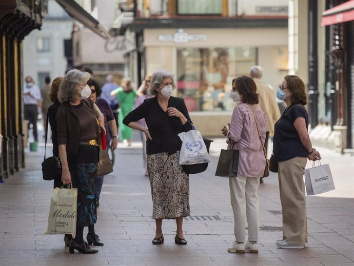 Varias personas protegidas con mascarillas conversan en una calle del centro de la ciudad, tras el nuevo acuerdo de Gobierno en el cual el uso de mascarillas será obligatorio también en la vía pública y en espacios cerrados cuando no se pueda garantizar