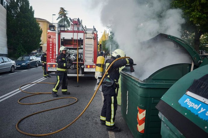 Una dotación de bomberos apaga un contenedor de basura que los manifestantes han prendido en señal de protesta durante la manifestación celebrada en el barrio de la Txantrea de Pamplona en apoyo al preso etarra Patxi Ruiz, quien se ha declarado en huelg
