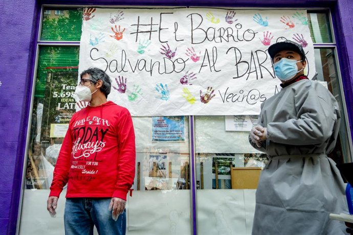 Dos personas al lado de un cartel donde se puede leer "El Barrio salvando al barrio" en la Asociación de Vecinos Parque Aluche 