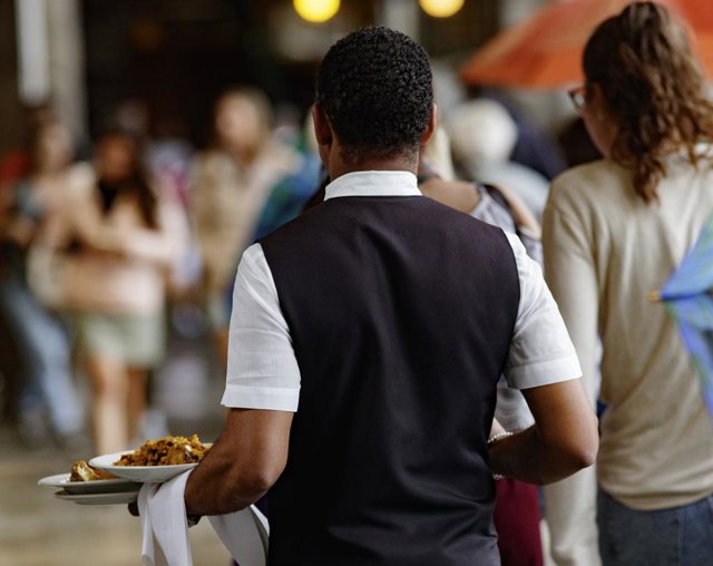 Un camarero porta los platos de los clientes en Madrid.