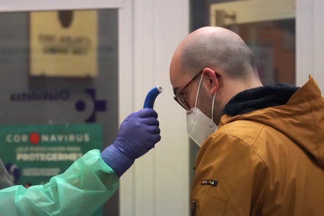 Un sanitario toma la temperatura a uno de los paciente diagnosticados con COVID-19 a los que no se le realizó previamente test antes de realizar el cribado, en el centro de centro de salud de Osakidetza del casco viejo de Bilbao.