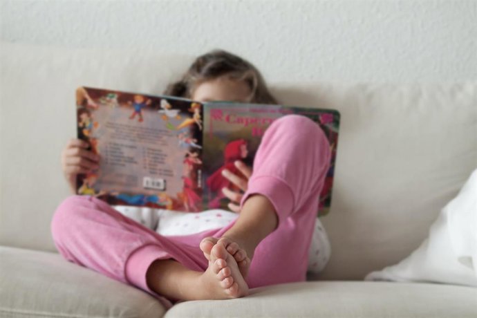 Una niña leyendo un cuento en su casa