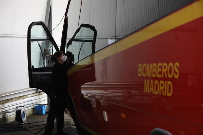 Una mujer desinfecta el interior de un vehículo utilizado por los Bomberos de la Comunidad de Madrid