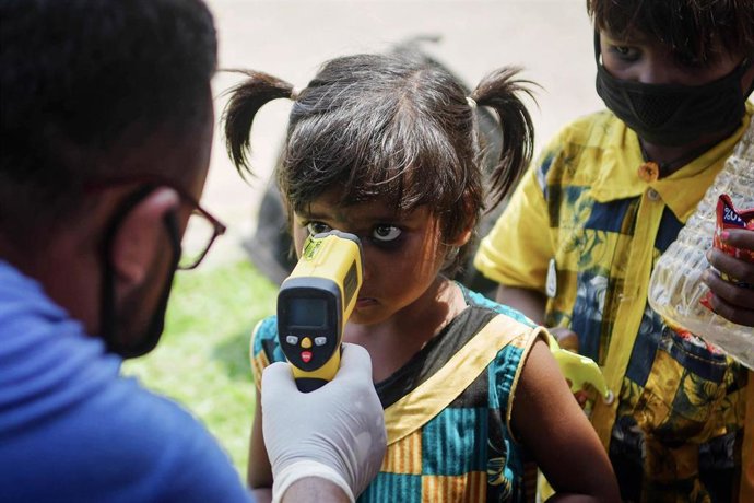 Un hombre toma la temperatura a una niña en la frontera de Joypur, donde llegan los trabajadores migrantes en el Shramik Express. 17 May 2020, India. 