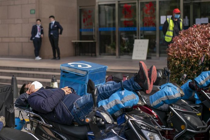 Un repartidor descansa en su motocileta en Shanghai.