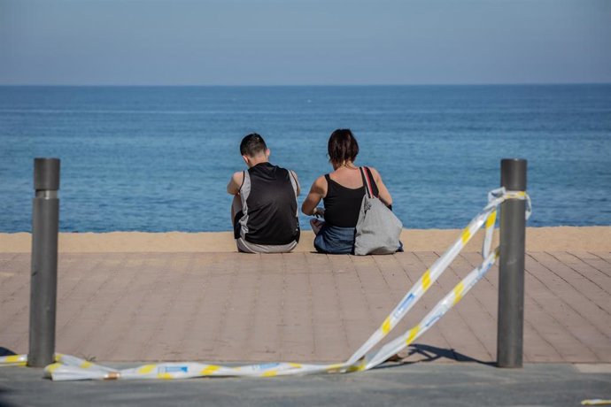 Dos jóvenes sentados en una playa