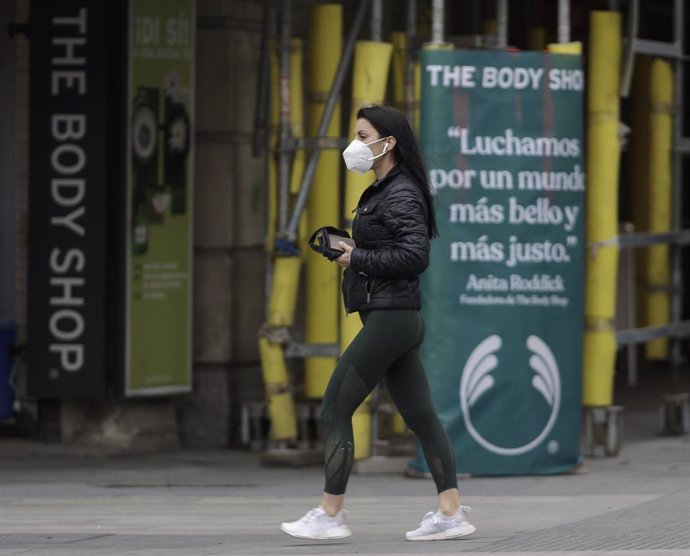 Una mujer camina con una mascarilla por la capital donde desde este pasado lunes las 2.882 farmacias madrileñas han entregado de forma gratuita siete millones de mascarillas FFP2 modelo KN95. En Madrid, (España), a 12 de mayo de 2020.