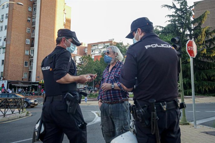Dos policías nacionales identifican a un hombre durante una protesta contra la gestión del Gobierno ante la pandemia en Alcorcón (Madrid) el 20 de mayo de 2020