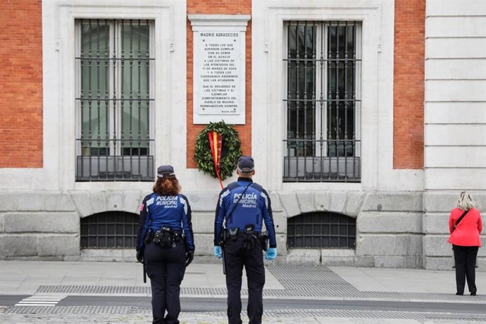 Dos agentes de la Policía Municipal guardan un minuto de silencio frente al edificio de la Real Casa de Correos