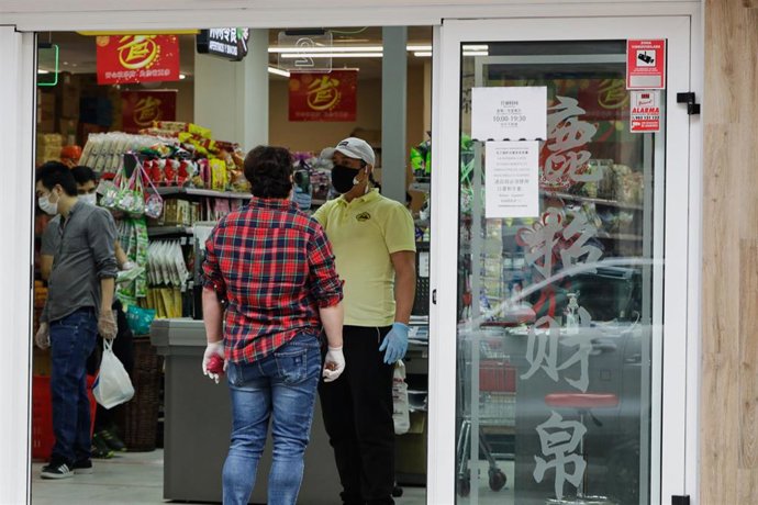 Un trabajador le toma la temperatura a un cliente a la entrada de un supermercado chino