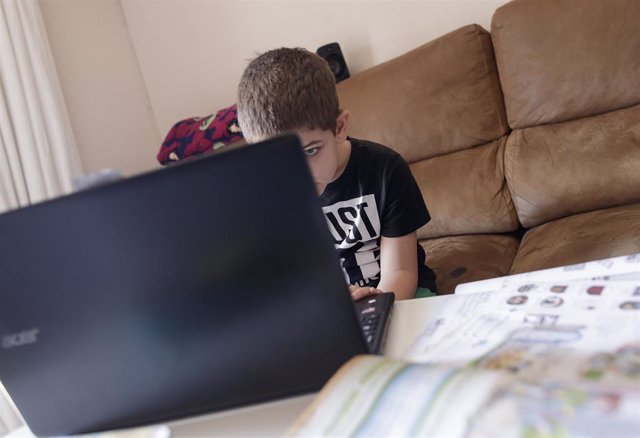 Un alumno de primaria hace los deberes de la asignatura de Inglés con varios libros y un ordenador